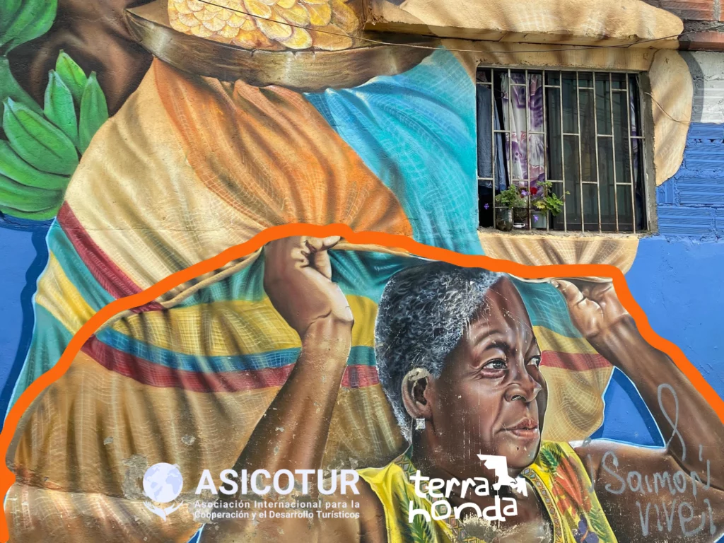 Mural en Manrique. Costelaciones. Comuna 3. Medellín. Mujer afrodescendiente cargando plátanos, gallina y objetos tradicionales.