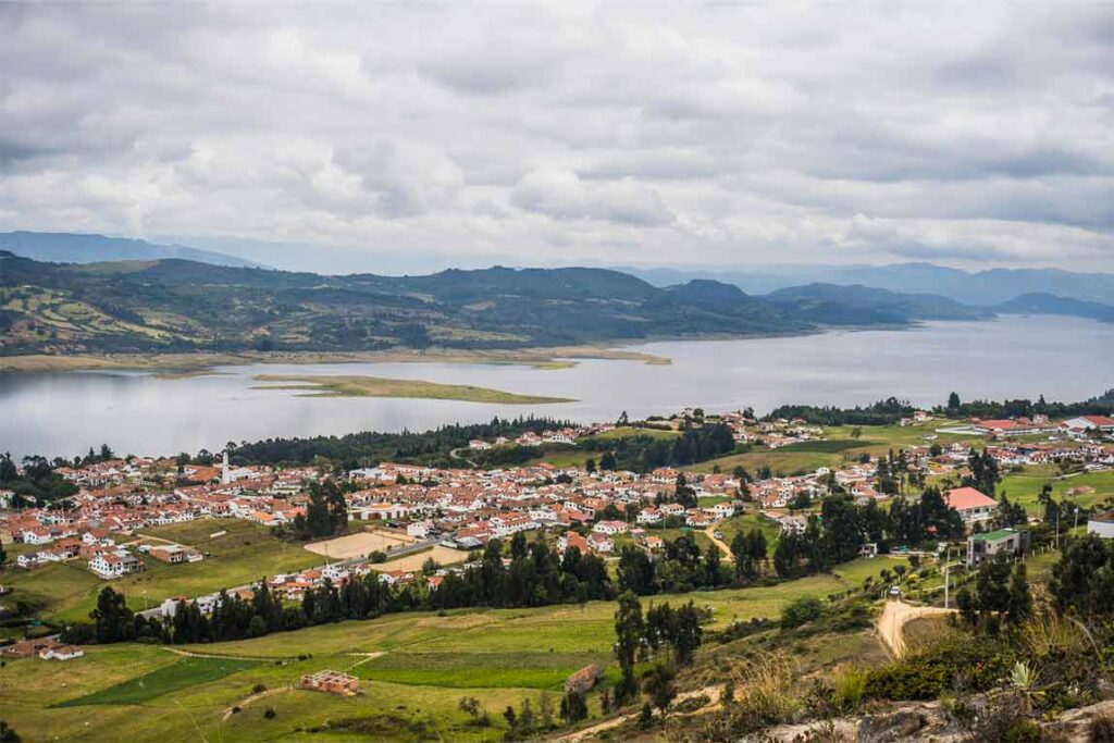 Vista de Guatavita, pueblo colonial con arquitectura blanca, y la laguna de fondo entre montañas.