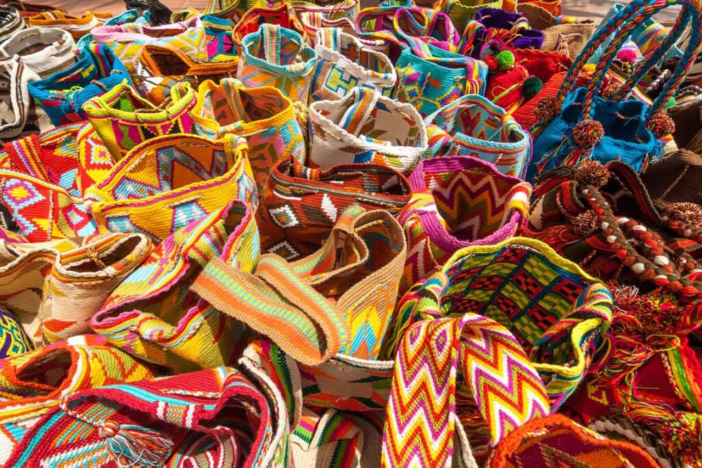 Variedad de mochilas Wayuu tejidas a mano, con patrones coloridos y formas geométricas tradicionales.