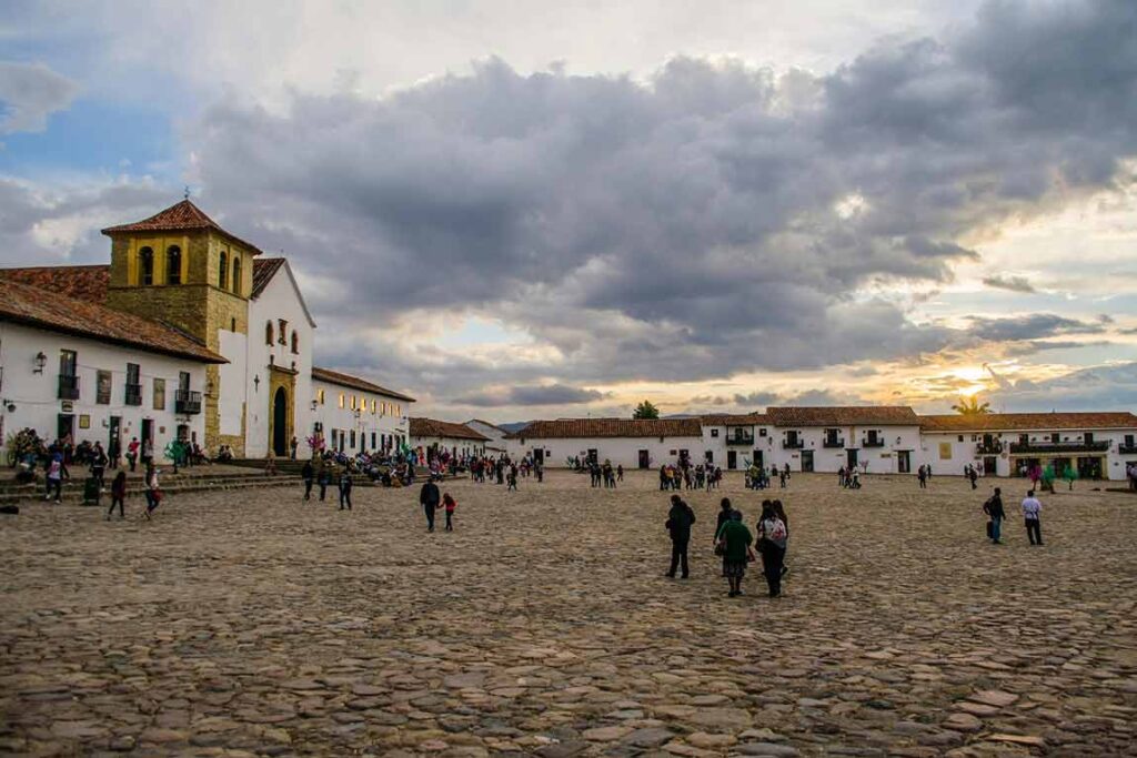 Plaza principal de Villa de Leyva, empedrada y rodeada de arquitectura colonial, con visitantes caminando.