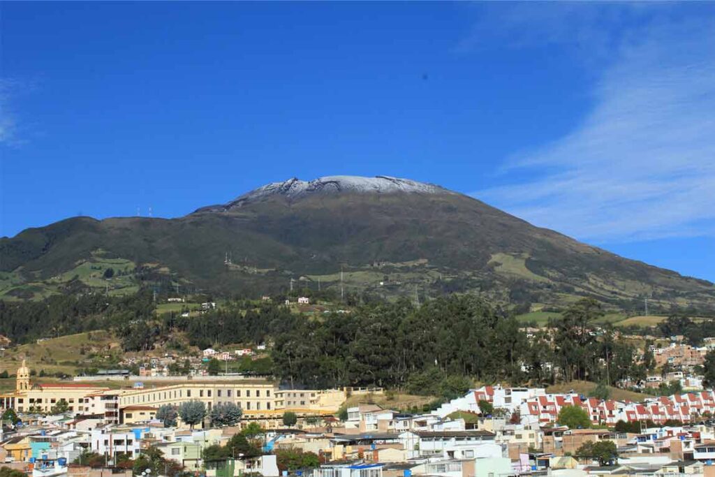 Volcán Galeras al fondo de la ciudad de Pasto, con su cumbre nevada destacando sobre el paisaje urbano.